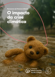 Uma criança parda está na grama com olhar sério.